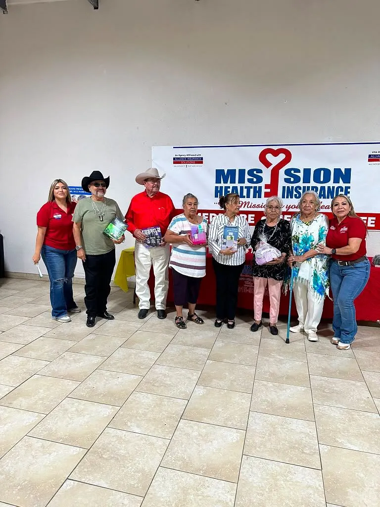 Grupo de seniors con bolsas de regalo frente al banner de Mission Health