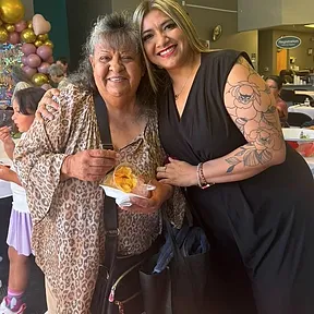 Lily abraza a una clienta mayor en un evento comunitario
